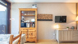 A hotel room with a wooden cabinet, a television, a lamp, and a bed with a patterned bedspread. - Zen Altitude- Piscine partagée (Chamrousse)