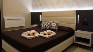 Een moderne hotelkamer met een groot bed, een nachtkastje en een wandgemonteerde airconditioning.