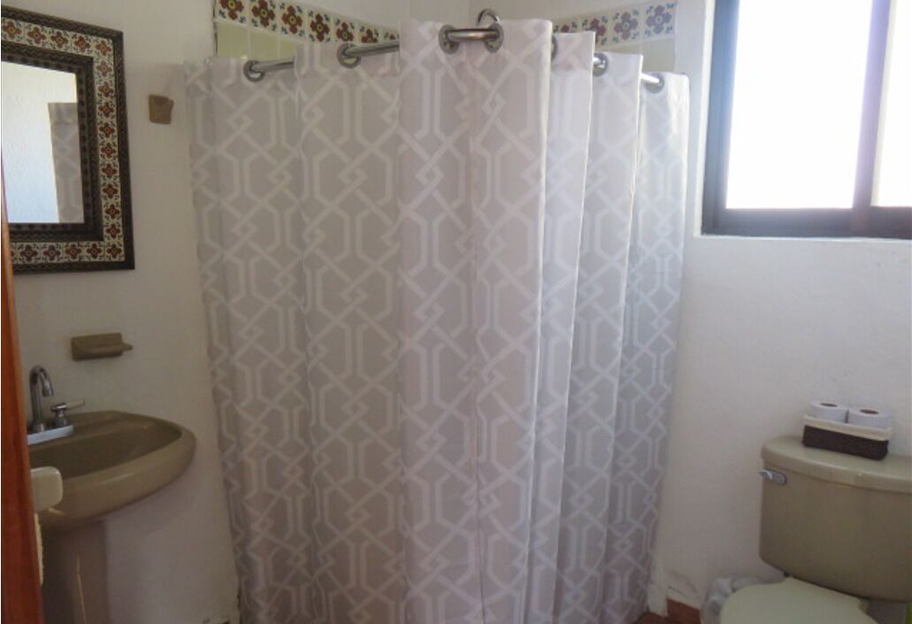 A bathroom with a patterned shower curtain, a sink, and a toilet.
