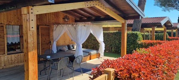 Eine Holzhütte mit einer überdachten Veranda, einem Esstisch und Stühlen.