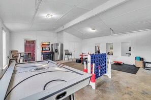 Un grand espace intérieur comprenant une table de billard, un réfrigérateur et un coin salon avec des chaises et une table.