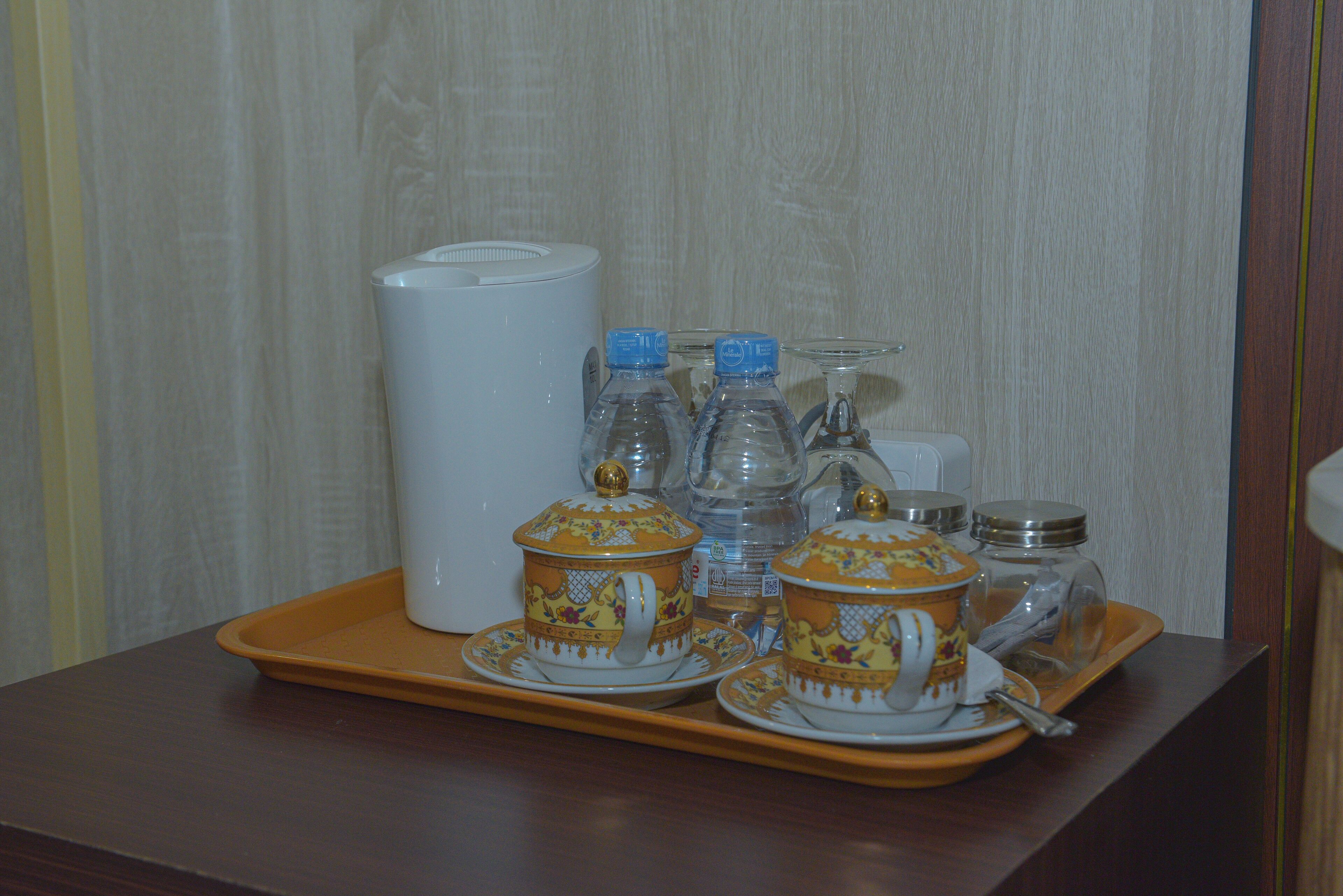 A tray with tea service and water bottles on a wooden table.