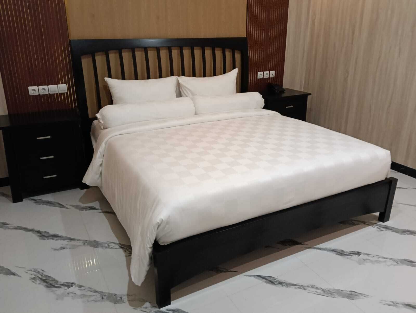 A neatly made bed with a checkered bedspread, a wooden headboard, and two bedside tables with drawers.