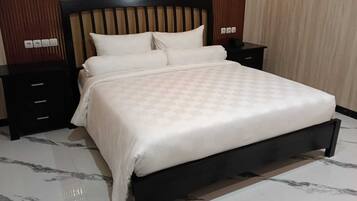 A neatly made bed with a checkered bedspread, a wooden headboard, and two bedside tables with drawers.