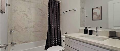 A modern bathroom with a bathtub, toilet, and vanity.