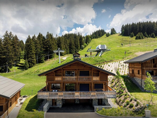 Eine Holzhütte mit Balkon, einer Seilbahn und einem Bergpanorama.