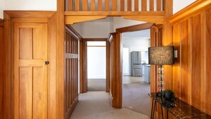 Un couloir en bois mène à une cuisine équipée d’un réfrigérateur moderne.