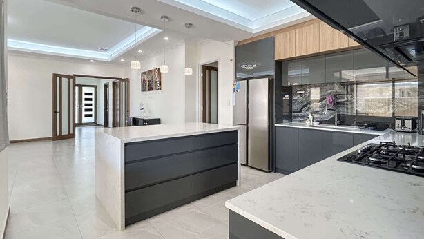 A modern kitchen with a central island, built-in appliances, and a skylight. - Spacious 4 bed home with open plan living (Southern River)