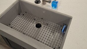 A kitchen sink with a modern faucet, a grid drain, and a soap dispenser.