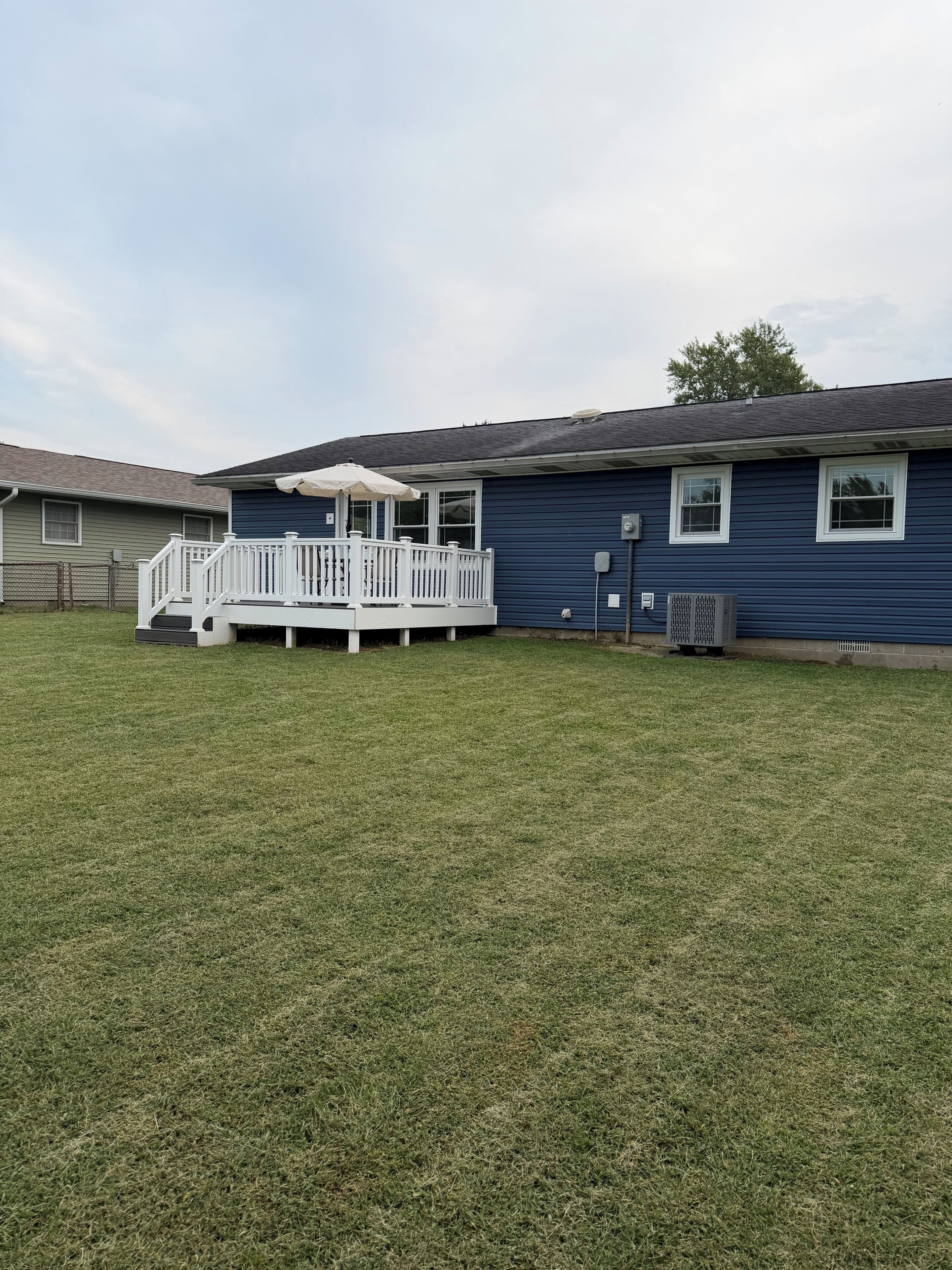 A residential house with a fenced backyard, a covered deck, and a garage.