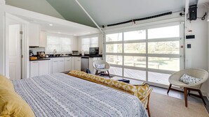 A bedroom with a large bed, a kitchenette, and a sliding glass door leading to an outdoor area. - Paddler's End | Perfect Jackson Creek Location (Deltaville)