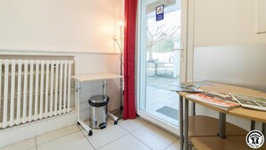Ein Zimmer mit Heizkörper, kleinem Mülleimer, Tisch mit Zeitschriften und einer Tür mit Parkschild.
