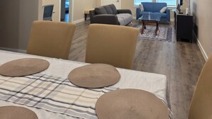 Un salon spacieux comprenant un coin repas, un ventilateur de plafond et de grandes fenêtres.