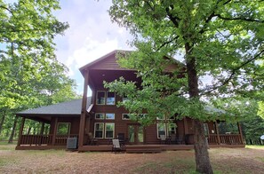 A two-story log cabin with a porch, multiple windows, and a deck area. - Serenity, secluded 4-bedroom, 3 bath spacious lux cabin with lots of amenities (Ringold)