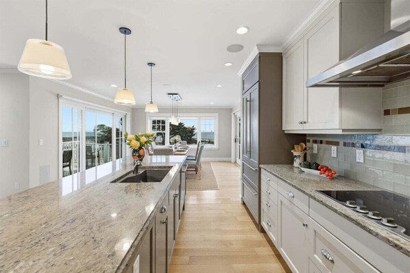 A modern kitchen with granite countertops, stainless steel appliances, and pendant lighting.