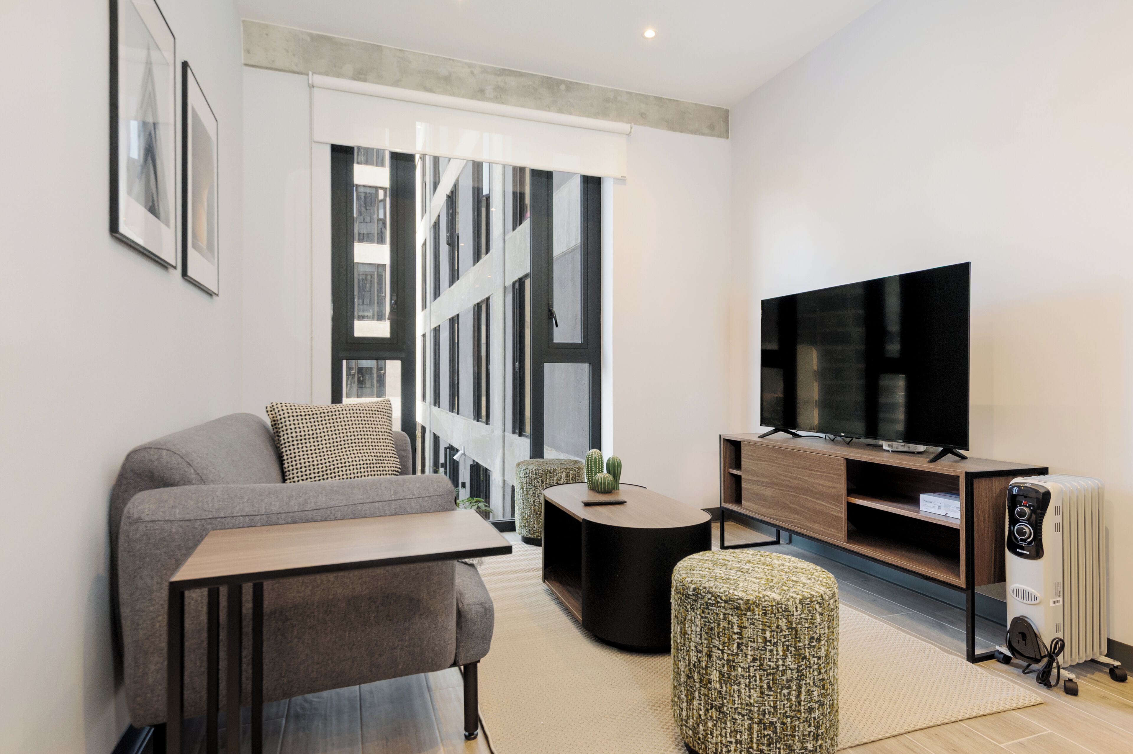 Ein modernes Wohnzimmer mit einem grauen Sofa, einem Couchtisch, einem Fernseher und einer Heizung.