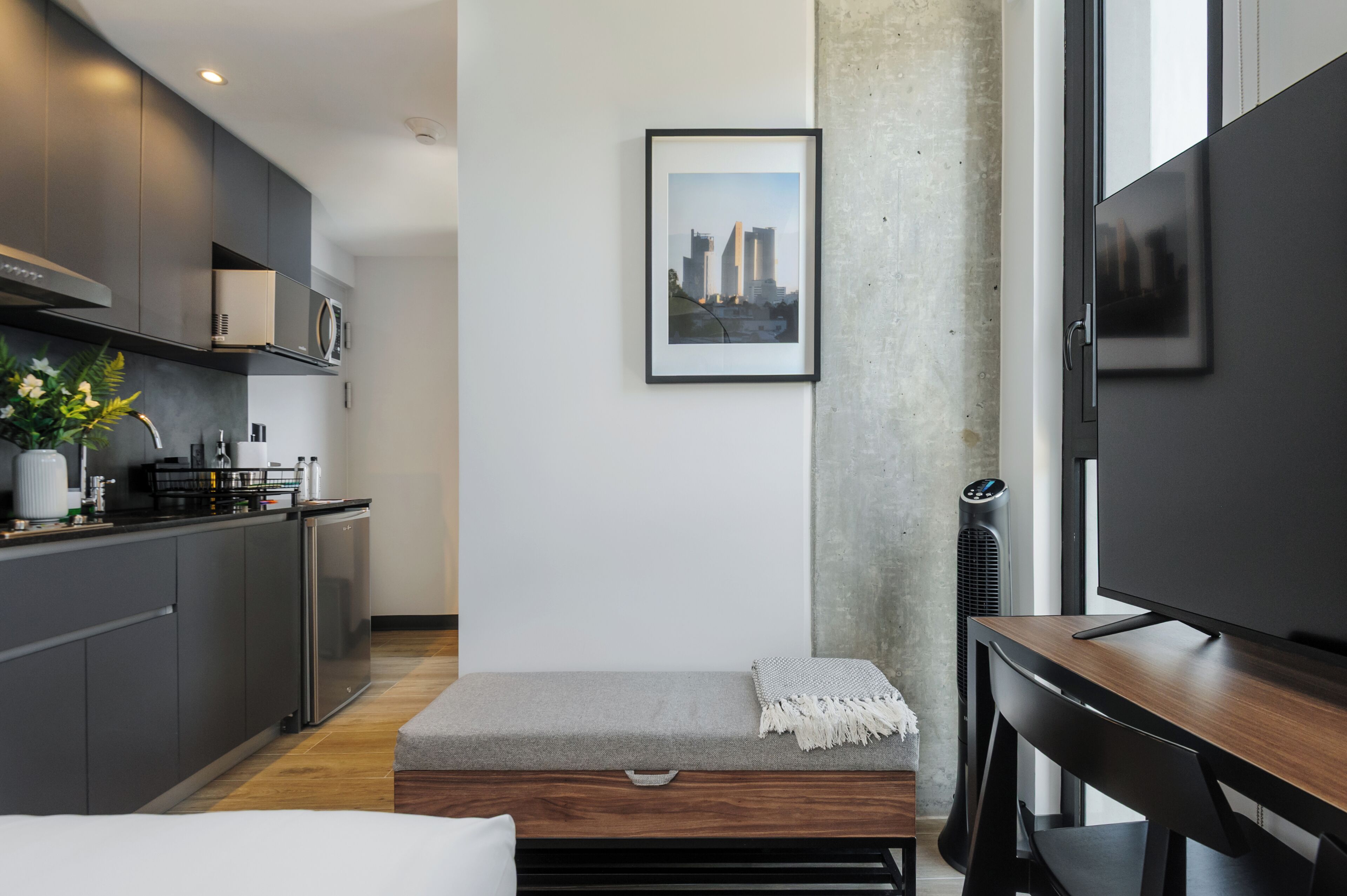 Une cuisine moderne avec des meubles gris, un four à micro-ondes et un petit coin repas comprenant un banc et une table.