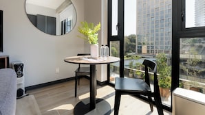 A modern room with a round table, chairs, a potted plant, and a large window offering a city view. - Interlomas by Wynwood House (Huixquilucan)
