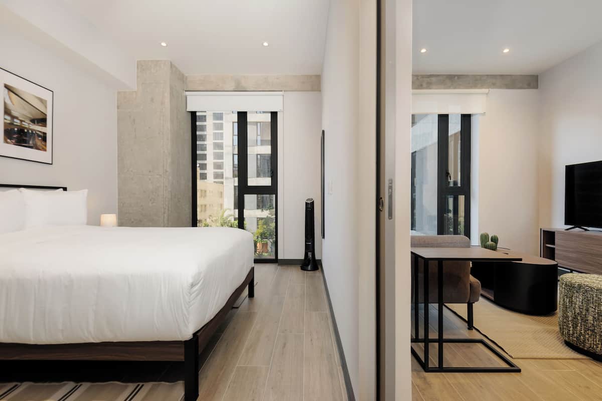 A modern hotel room with a large bed, a desk, and a flat-screen TV.