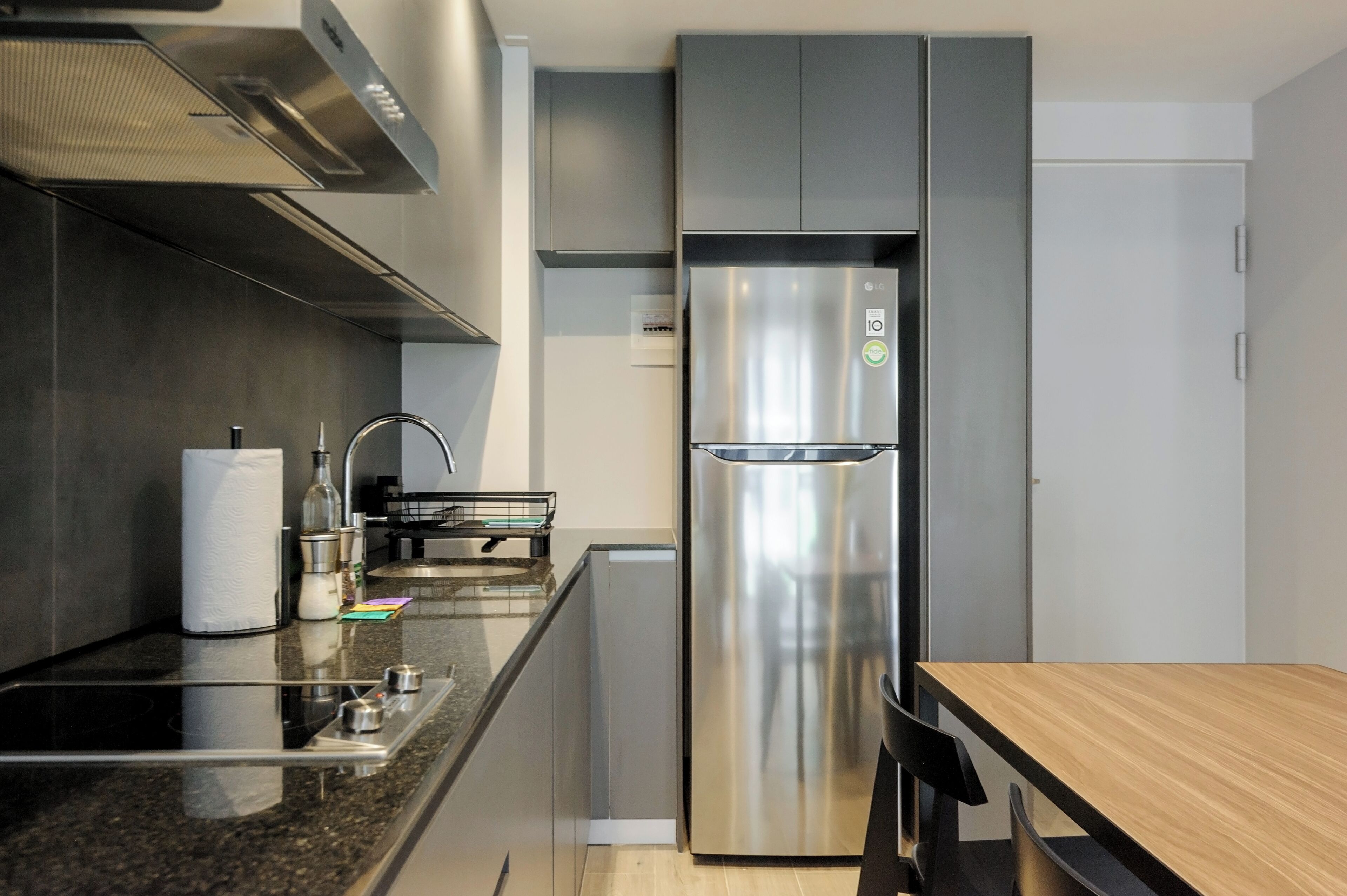 A modern kitchen with a stainless steel refrigerator, a built-in oven, and a granite countertop.
