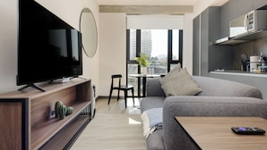 A modern living room with a flat-screen TV, a sofa, a coffee table, and a dining area with a small table and chairs. - Interlomas by Wynwood House (Huixquilucan)