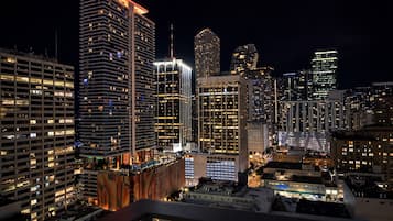 A nighttime cityscape with high-rise buildings, including a prominent hotel with a lit red roof and multiple floors.