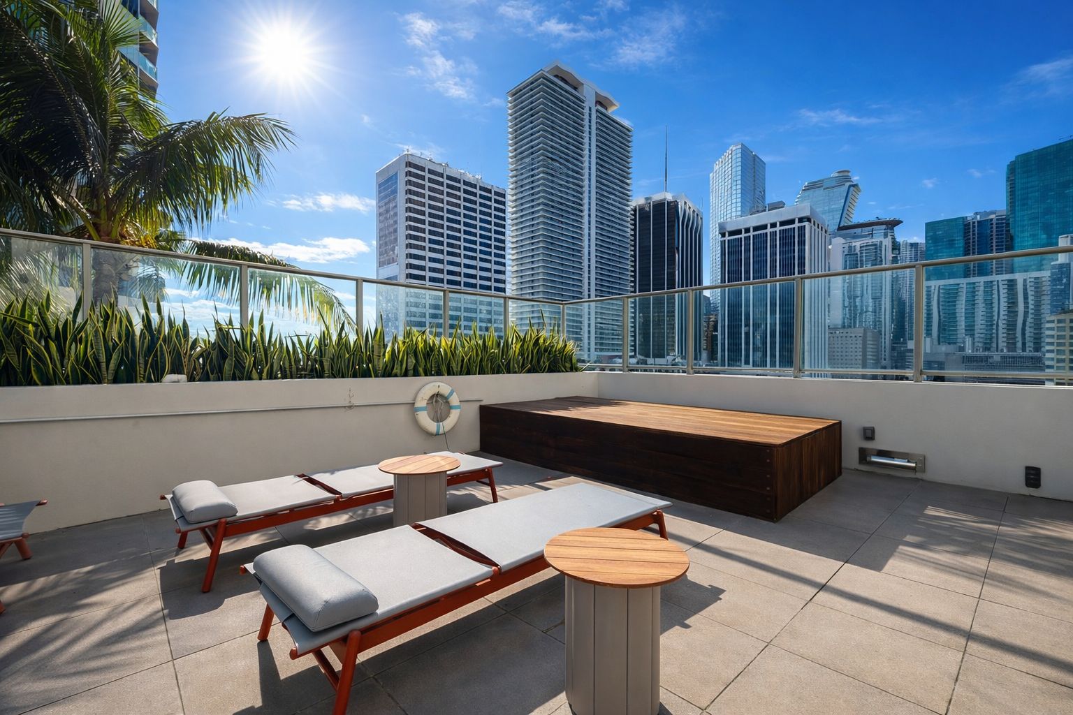 A rooftop terrace with lounge chairs, a wooden bench, and a view of the city skyline.