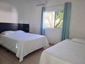 A hotel room with a bed, a nightstand, and a window with curtains. - 3-bedroom house in brilliant Playa San Blas with AC comfort (Playa San Blas)