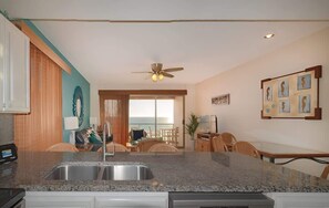 Eine Küche mit Granit-Arbeitsplatten, Deckenventilator und Essbereich mit Stühlen und Tisch.