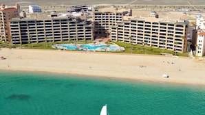 Un hôtel situé sur la côte, doté d’une grande piscine, de plusieurs bâtiments et d’un voilier amarré sur l’eau.