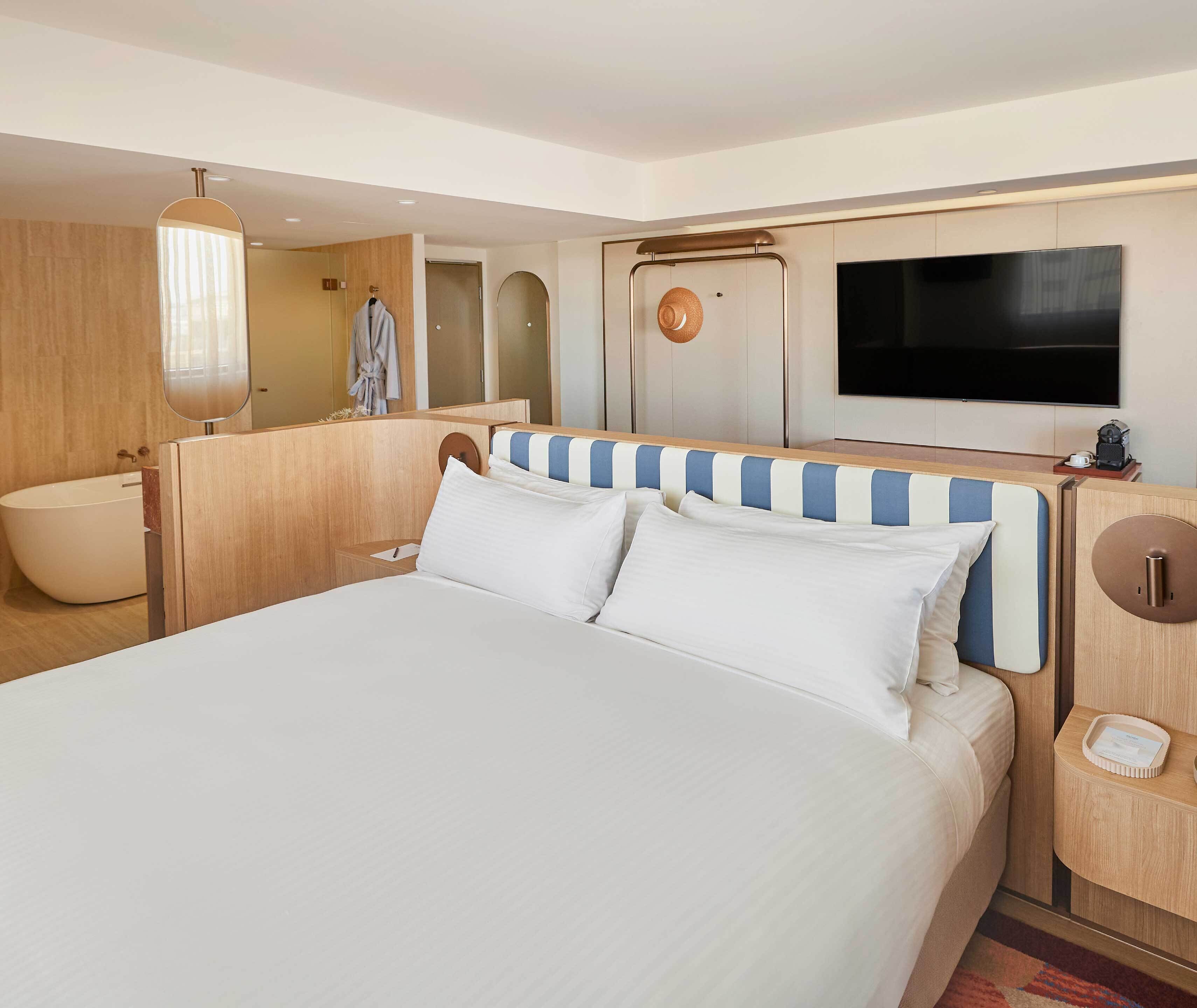 Ein Hotelzimmer mit einem großen Bett, einem Fernseher, einem Badezimmer und einem Holz-Kopfteil.