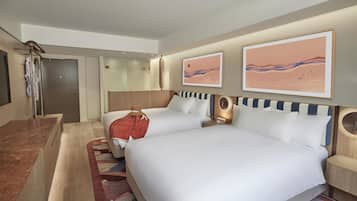 A hotel room with two beds, a bathroom, and artwork on the walls.