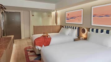A hotel room with two beds, a desk, and a mirror.