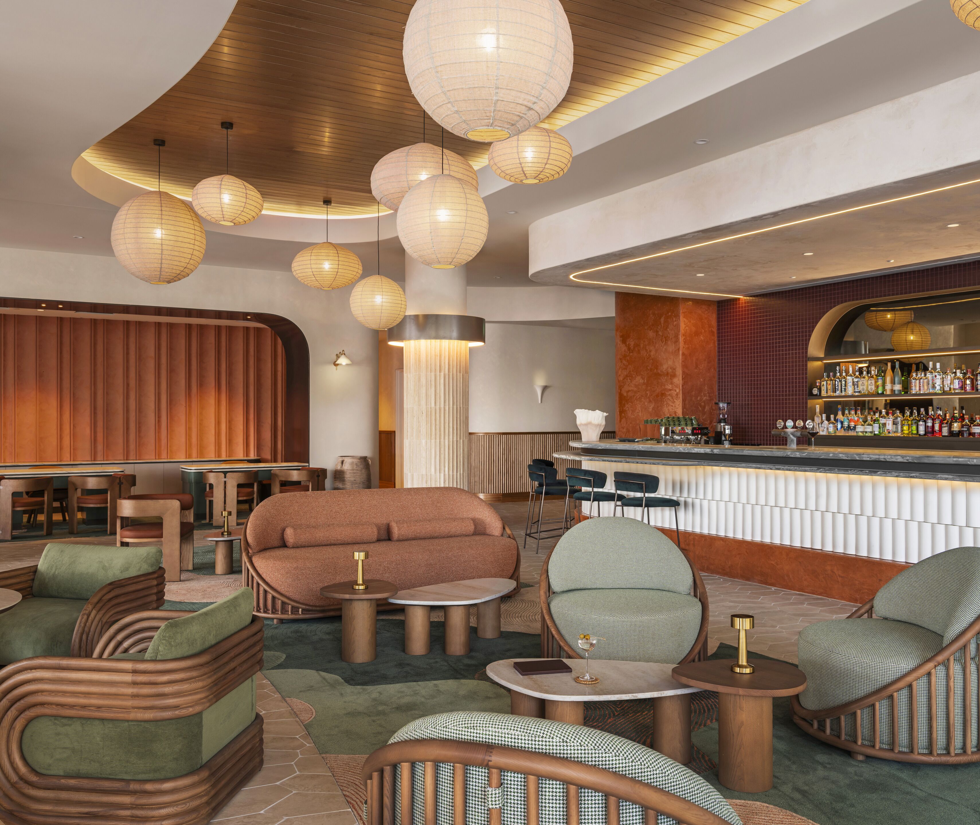 A modern bar area with round tables, bar stools, and a variety of seating options including sofas and chairs.