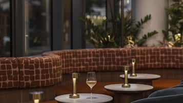 A modern interior with round tables, a glass wine glass, and a patterned seating area.