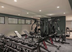 Een sportschool met diverse fitnessapparaten, waaronder gewichten, banken en krachttoestellen.