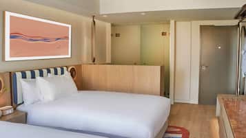 A hotel room with two beds, a large mirror, a painting on the wall, and a wooden floor.