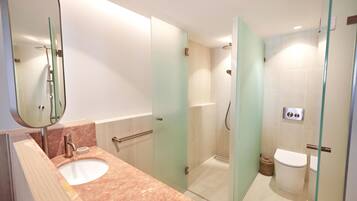 A modern bathroom with a glass-enclosed shower, a sink with a marble countertop, and a toilet.