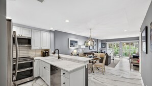 A modern kitchen with white cabinets, stainless steel appliances, and a marble countertop. - Updated OCEANVIEW 2 bedroom in East Beach! (Kiawah Island)