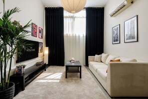 A modern living room with a flat-screen TV, a sofa, a coffee table, and a large potted plant. - Nasr City Loftique Noir (Cairo Governorate)