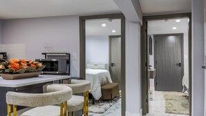 A modern kitchen with a microwave, a bowl of flowers, and a dining area with chairs.