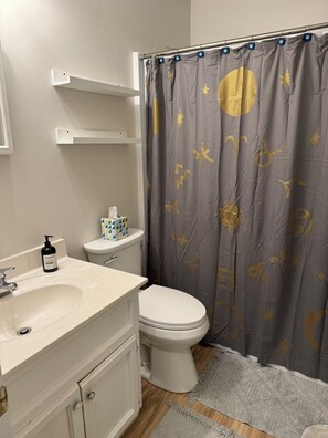 A bathroom with a white sink, toilet, and shower curtain with a celestial design.