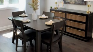 A dining area with a dark wooden table, six chairs, a vase with dried plants, and two wall-mounted lamps. - Luxury Townhome w/ Private Elevator (Newmarket)