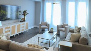 A modern living room with a sofa, armchairs, a coffee table, and a TV. - Luxury Townhome w/ Private Elevator (Newmarket)