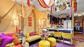 A vibrant living room with a sofa, ottomans, a glass coffee table, and a dining area with yellow chairs. - Condos Near Beach & Golf w/ Wifi, Balcony, Resort Pool, Hot Tub & Fishing (North Myrtle Beach)