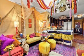 A vibrant living room with a sofa, ottomans, a glass coffee table, and a dining area with yellow chairs. - Condos Near Beach & Golf w/ Wifi, Balcony, Resort Pool, Hot Tub & Fishing (North Myrtle Beach)