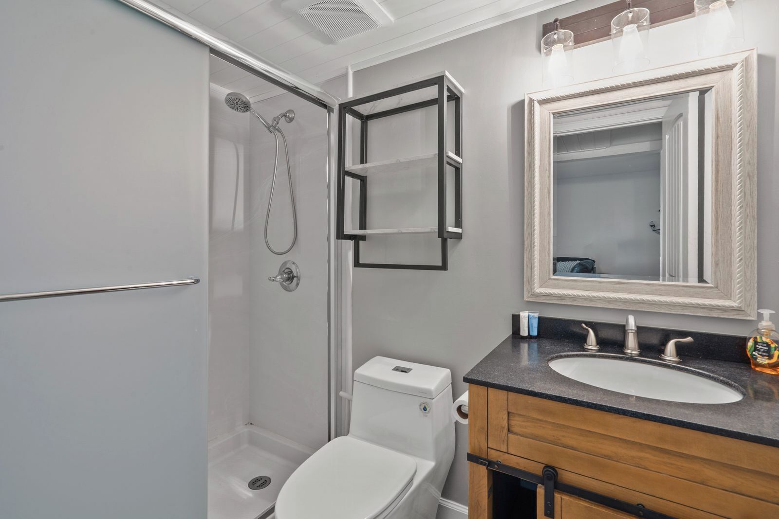 Ein Badezimmer mit Dusche, Toilette, Waschtisch und Spiegel.