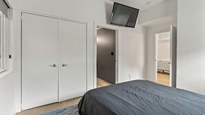 A bedroom with a bed, a wardrobe, and a television mounted on the wall. - SLC downtown hub (Salt Lake City)