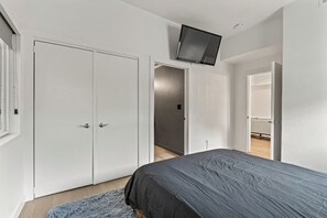 A bedroom with a bed, a wardrobe, and a television mounted on the wall. - SLC downtown hub (Salt Lake City)