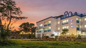 A multi-story hotel with balconies and a stone wall in front. - Gyeongju Breeze Spa Pension (Gyeongju)